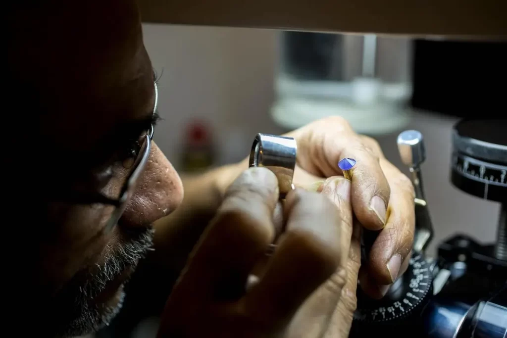 An Artisan inspecting the gemstone that is being faceted.